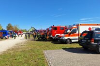 Einsatzkräfte zwischen Fahrzeugen von Feuerwehr, Rettungsdienst und THW