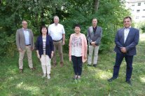 Sechs Personen stehen mit Abstand im Freien