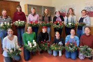 Personengruppe in einem Raum mit Adventskranz in der Hand