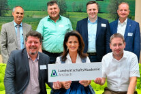 6 Männer und Michaela Kaniber, die Schild mit Aufschrift "LandwirtschaftsAkademie Ansbach" hält