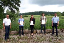 Fünf Personen stehen im Freien nebeneinander