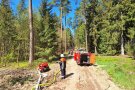 Feuerwehrmann vor Pumpe und Gerätewagen im Wald