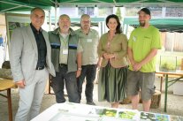 Mehrere Personen an einem Stand blicken in Kamera