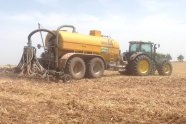 Traktor mit Güllefass bei der Düngung auf unbestelltem Ackerland