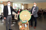 Zwei Männer zeigen runde Platte und Lebensmittel